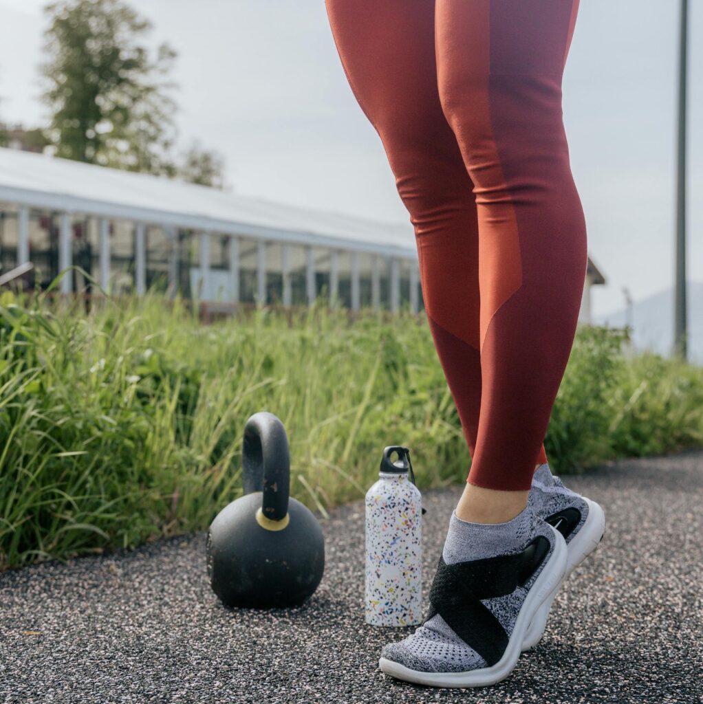 A person exercising outdoors with a kettlebell and water bottle, promoting fitness.
